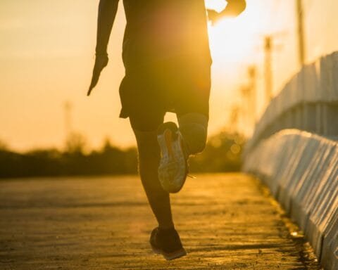 Silhouette of a young fitness man running on sunrise